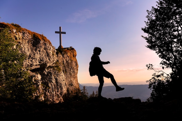 Silhouette d'adolescent marchant au sommet de la montagne au coucher du soleil voyageant seul