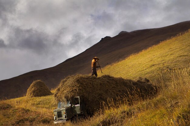 Photo silhouette d'agriculteur avec une fourche collectant du foin