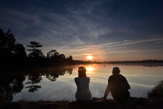 Silhouette d'amant avec le lever du soleil coloré de nuage à un lac