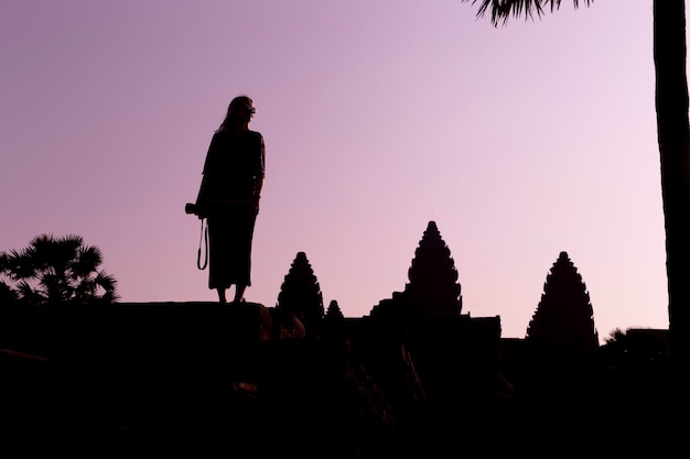 Silhouette d'Angkor Wat et fille voyageur avec appareil photo sur le lever du soleil. Angkor Wat - complexe de temples hindous au Cambodge