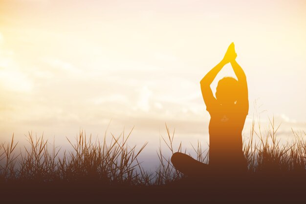 Silhouette Asie femme yoga sur la plage au coucher du soleil.