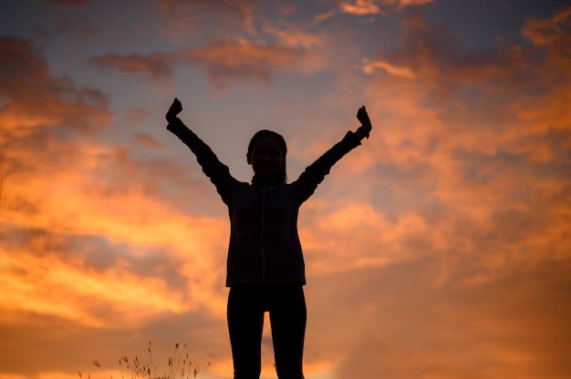 Silhouette au coucher du soleil, les femmes ont levé la main pour exprimer leur joie et leur bonheur.