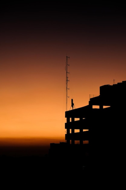 Photo silhouette d'un bâtiment de stationnement avec une vue magnifique sur le coucher de soleil