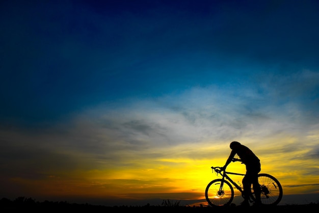 Silhouette bel homme asiatique à vélo au coucher du soleil