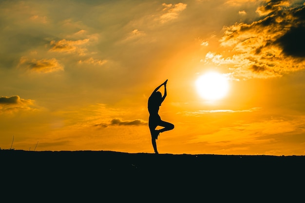 Silhouette d'une belle femme de yoga au coucher du soleil