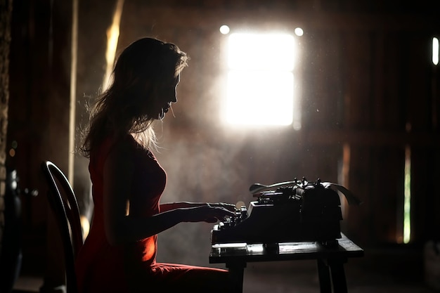 Silhouette d'une belle fille dans une robe rouge sur le fond d'une fenêtre dans une vieille maison