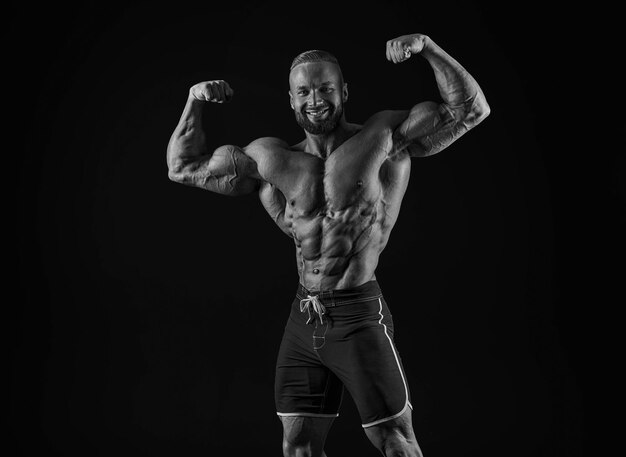 Photo silhouette d'un bodybuilder fort jeune athlète de fitness confiant avec un corps puissant et des abdos parfaits photographie en noir et blanc lumière dramatique médias mixtes