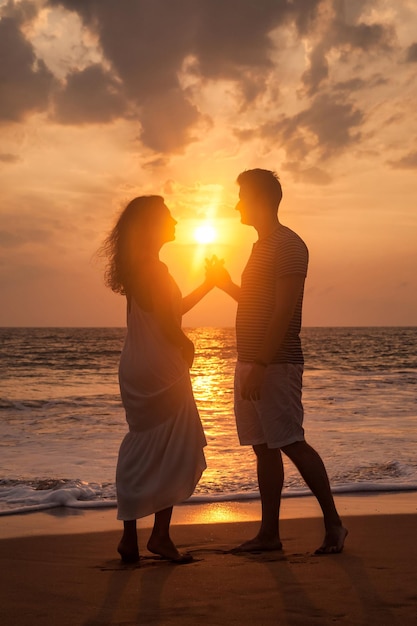 Silhouette charmant couple main dans la main sur une plage de sable tropicale au fond de coucher de soleil en mer Heureux homme et femme à la recherche de bonheur