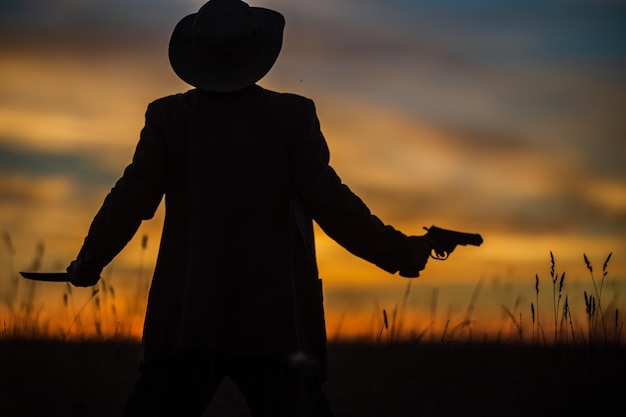 Silhouette d'un chasseur de démons et de vampires avec un ciel dramatique en arrière-plan Un homme avec un katana et un revolver Concept de fantaisie et d'halloween