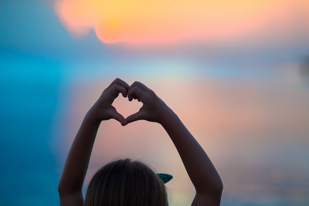 Photo silhouette de coeur faite par la main des enfants au coucher du soleil