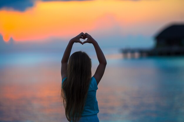 Silhouette de coeur faite par la main d'enfants au coucher du soleil