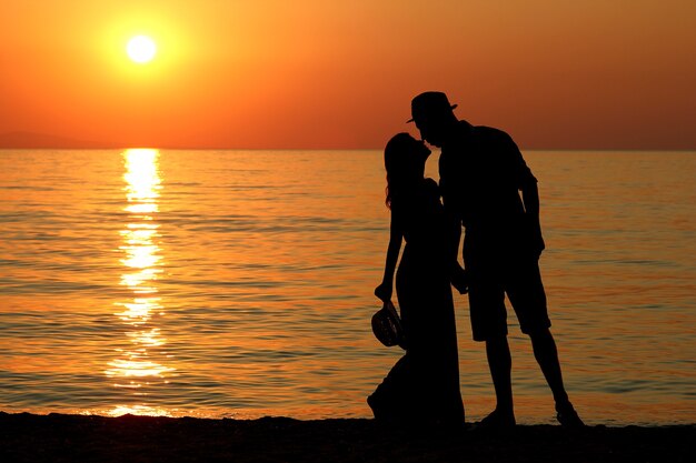 Silhouette d'un couple d'amoureux heureux au coucher du soleil au bord de la mer en Grèce