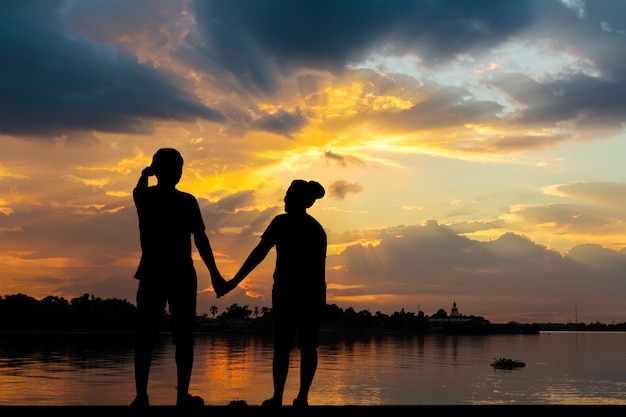 Silhouette de couple au bord de la rivière avec un beau coucher de soleil