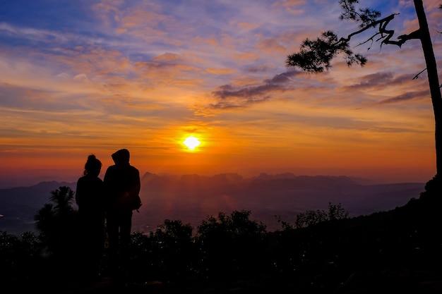 silhouette de couple au sommet d'une montagne au coucher du soleil