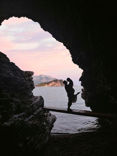 Silhouette de couple dans une grotte devant un magnifique paysage marin sur la plage de Mogren