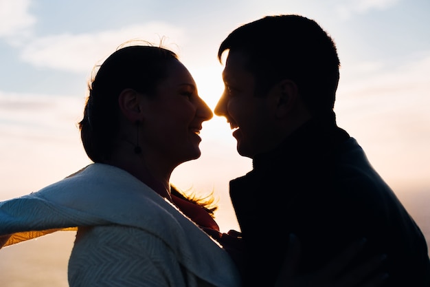 Silhouette de couple romantique au coucher du soleil se regarde