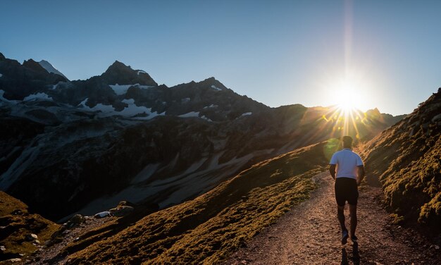 Une silhouette de coureur de train unique contre le ciel au lever du soleil en courant dans les montagnes