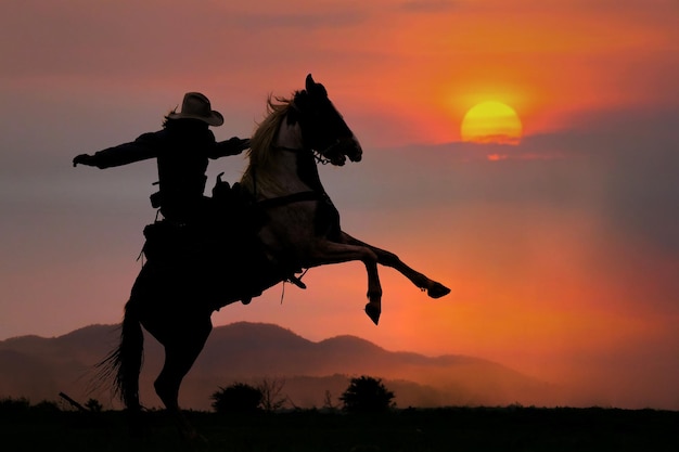 Photo la silhouette d'un cow-boy à cheval au coucher du soleil sur la montagne