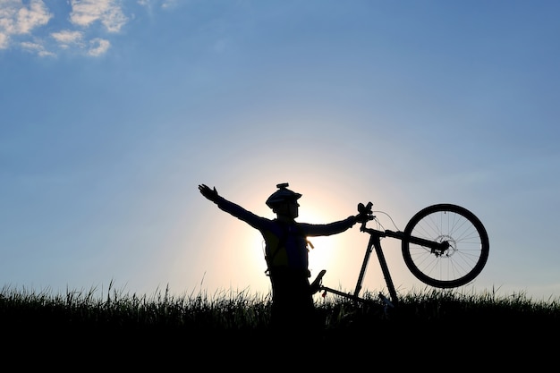 Silhouette d'un cycliste avec un vélo au soleil