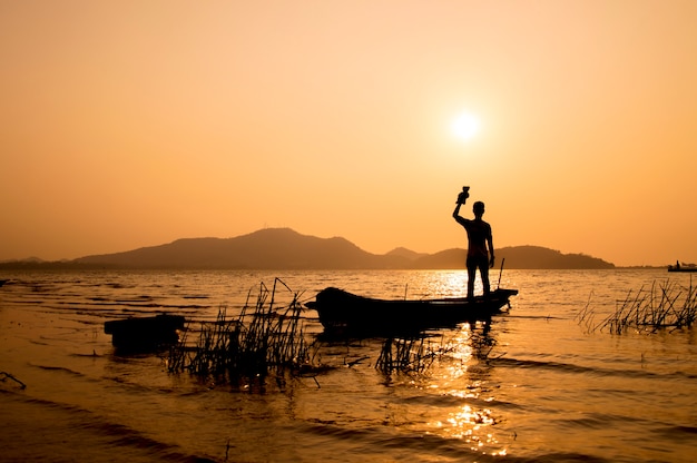 Silhouette, debout, bateau, coucher soleil