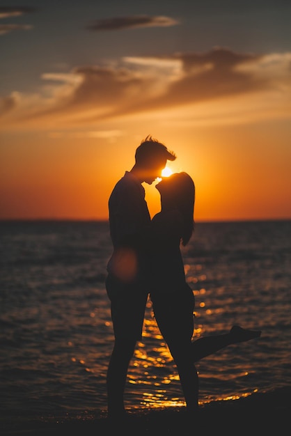 Silhouette de deux personnes se tenant la main contre la mer