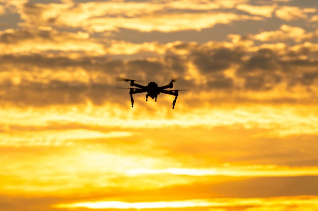 Silhouette drone volant au coucher du soleil