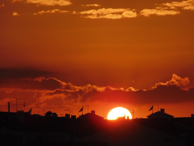 Silhouette du paysage urbain contre le soleil dans un ciel nuageux au coucher du soleil