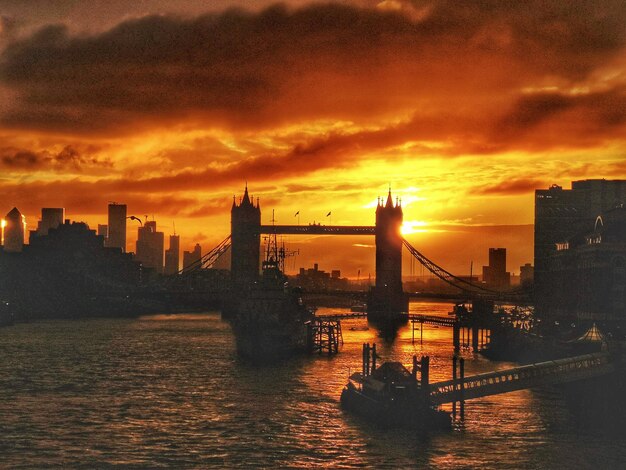 Photo silhouette du pont sur la rivière contre le ciel au coucher du soleil