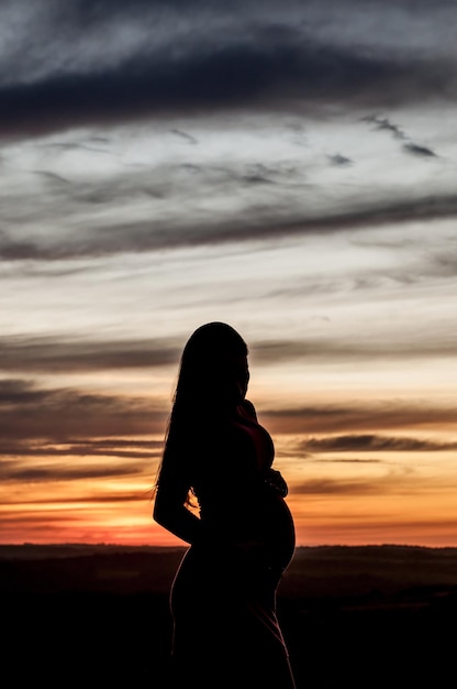 Silhouette enceinte au coucher du soleil orange