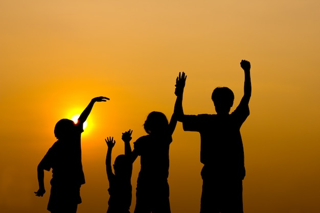 Silhouette d&#39;enfants jouant avec coucher de soleil