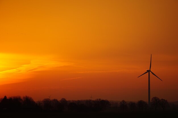 Photo silhouette d'éoliennes sur le terrain contre un ciel orange