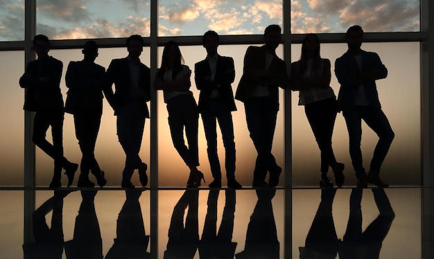 Silhouette d'une équipe commerciale debout à côté de la photo de la fenêtre du bureau avec espace de copie