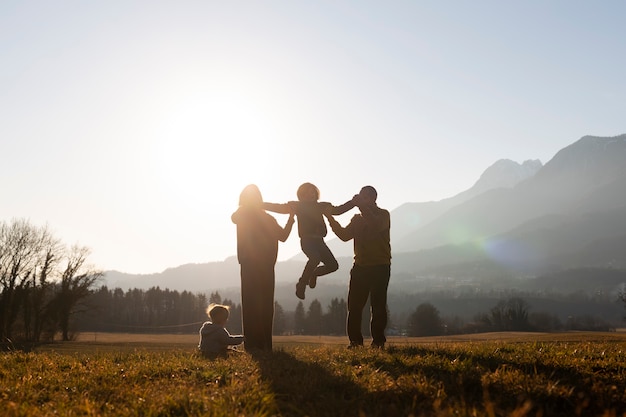 Silhouette familiale complète dans la nature au coucher du soleil