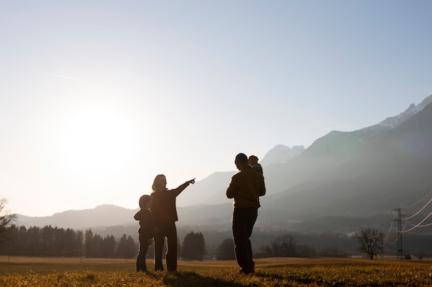 Photo silhouette familiale complète dans la nature au coucher du soleil