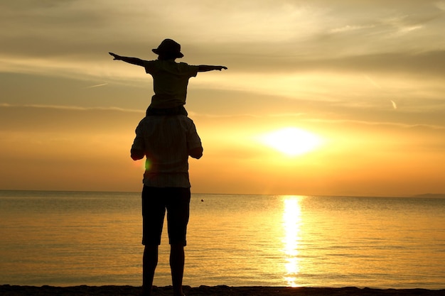 Silhouette familiale heureuse au coucher du soleil au bord de la mer