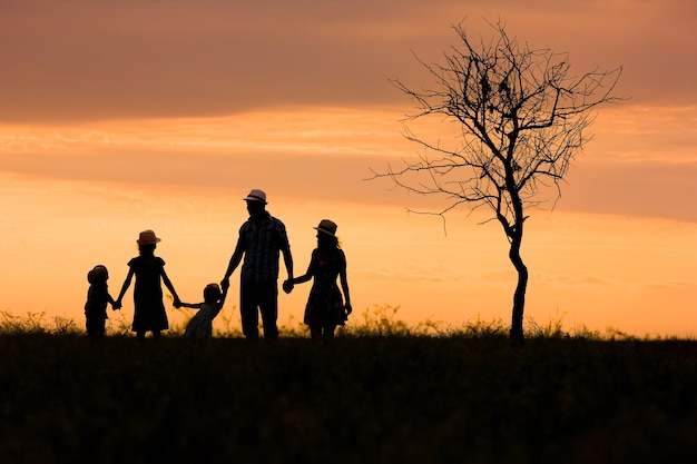 Une silhouette de famille heureuse sur la nature en arrière-plan du parc