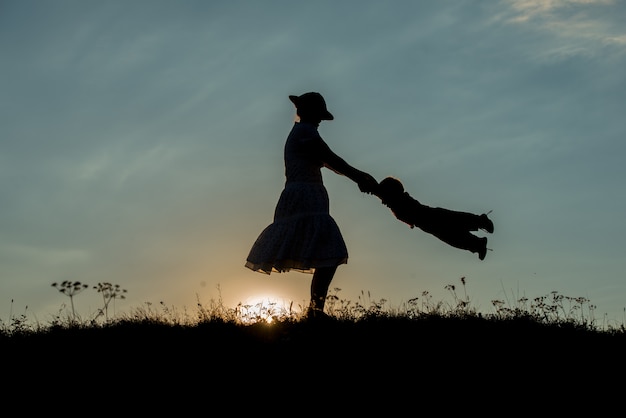 silhouette de famille heureuse, s&#39;amusant sur la falaise