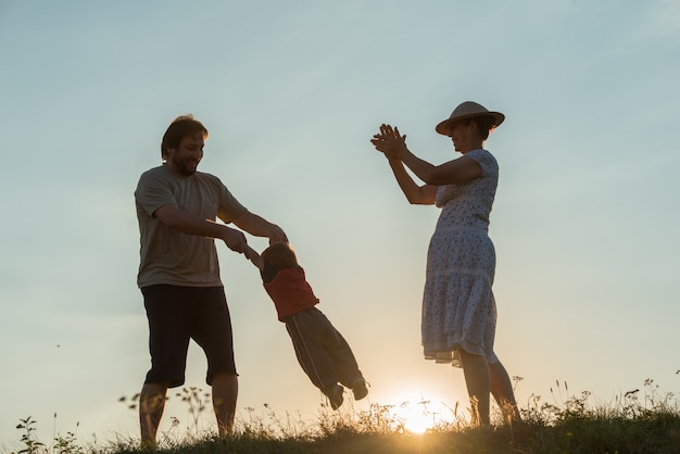 silhouette de famille heureuse, s&#39;amusant sur la falaise