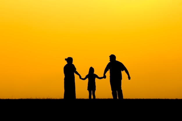 Photo silhouette d'une famille marchant au coucher du soleil