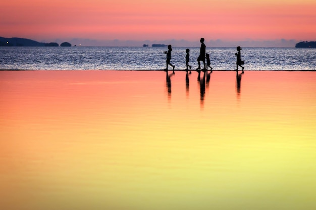 La silhouette de la famille marchant côte à côte sur la plage