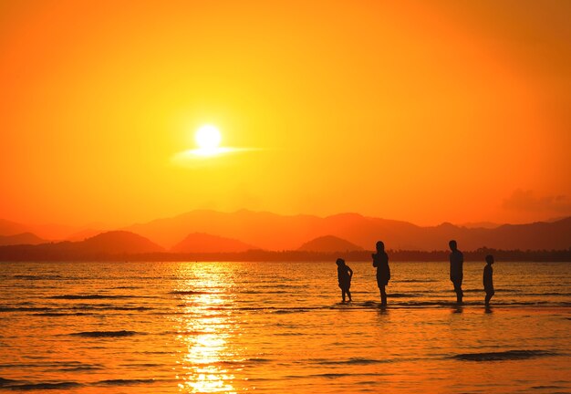 Silhouette de famille sur la plage au coucher du soleil
