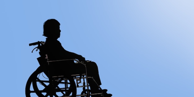 Photo silhouette de femme âgée handicapée et abattue assise dans son fauteuil roulant