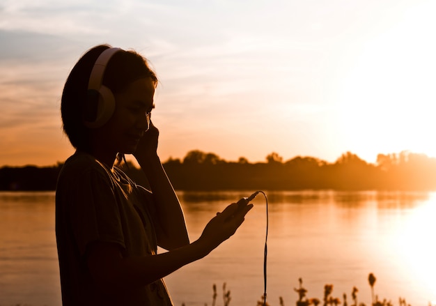Silhouette de femme à l&#39;aide de smartphone pour écouter la chanson