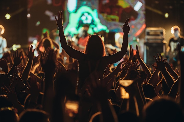 Silhouette d'une femme aux mains levées sur un concert
