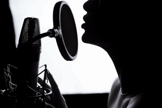 Silhouette d'une femme chantant une chanson dans un studio d'enregistrement noir et blanc