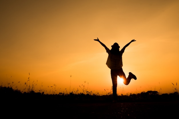 Silhouette de femme debout et coucher de soleil