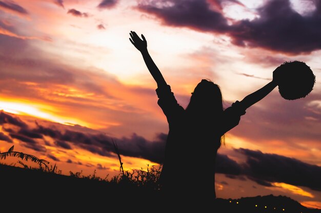 Photo silhouette d'une femme debout près d'un arbre contre le ciel au coucher du soleil