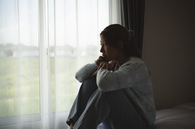 Silhouette d'une femme déprimée tristement assise sur le lit dans la chambre à coucher Des femmes tristes souffrant de dépression