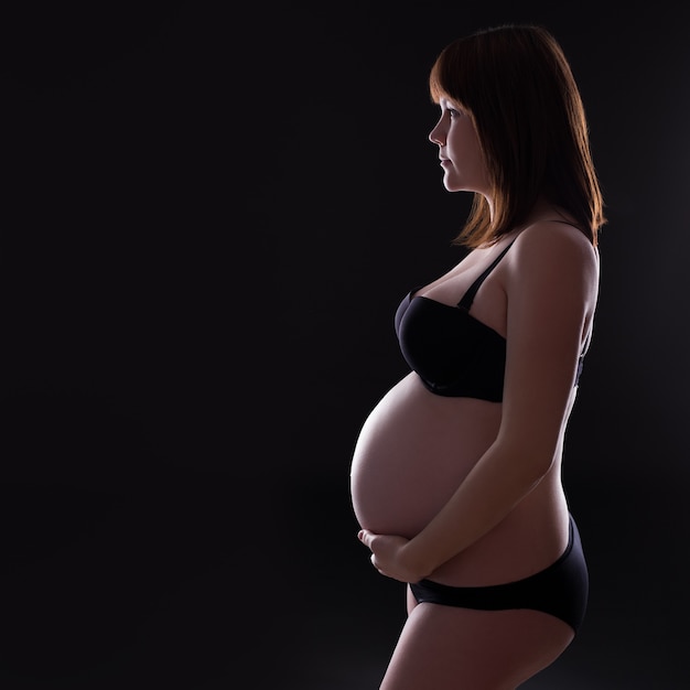 Silhouette de femme enceinte et copiez l'espace sur fond noir