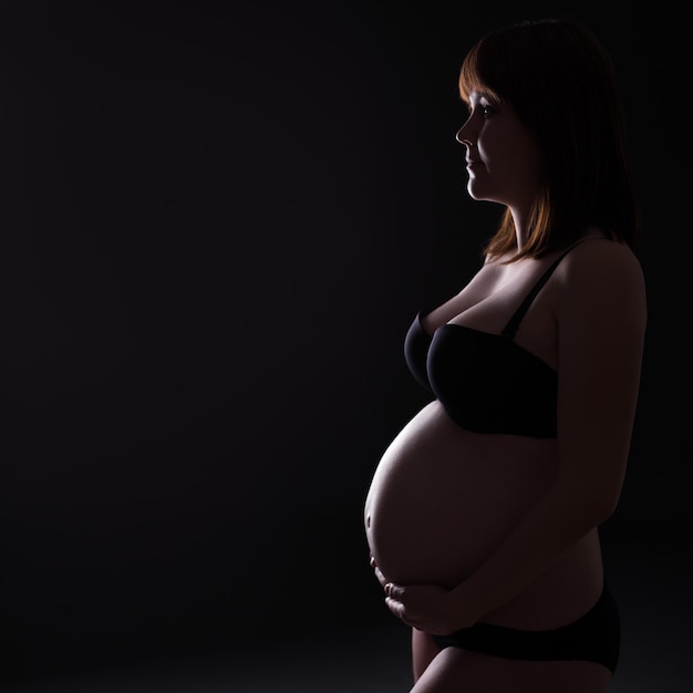 Silhouette de femme enceinte en lingerie et espace de copie sur fond noir